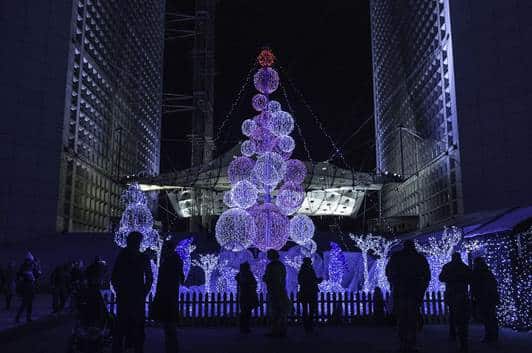Illuminated spiral Christmas tree lighting up a city square at night
