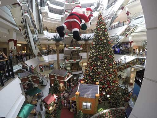 Santa figure abseiling past a giant Christmas tree in a shopping mall atrium